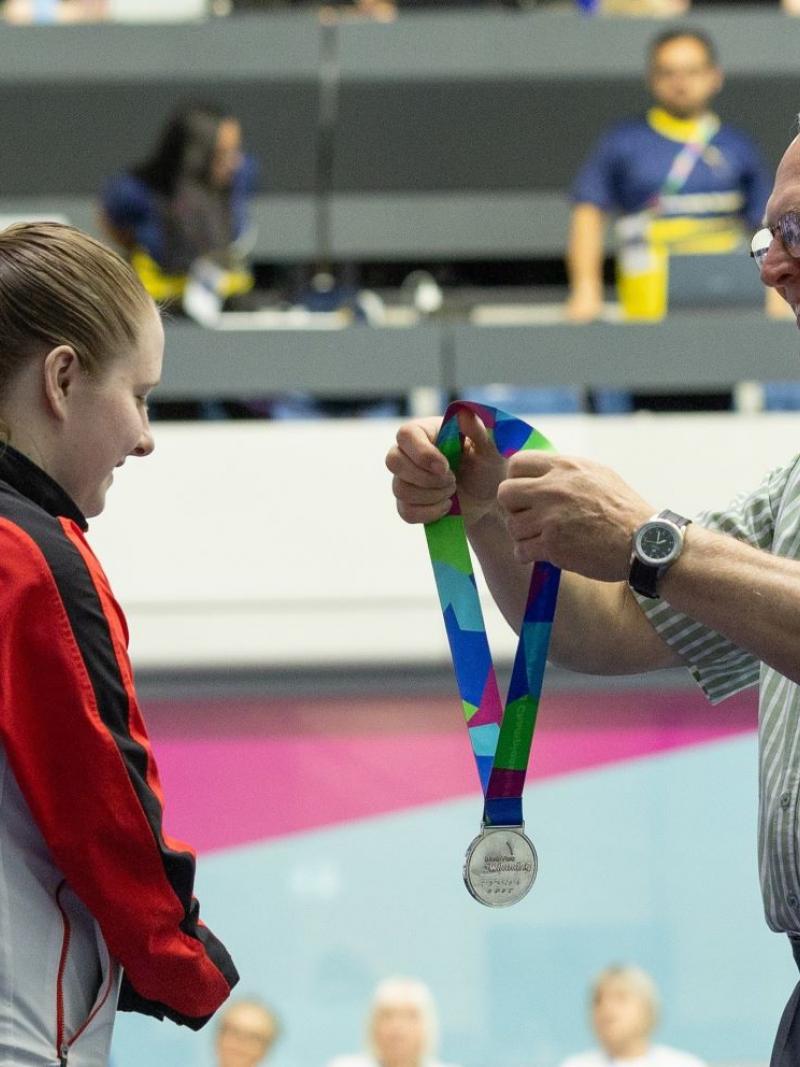 A man giving a silver medal to a female swimmer 