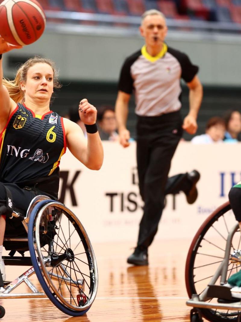 A female wheelchair basketball athlete throws the ball