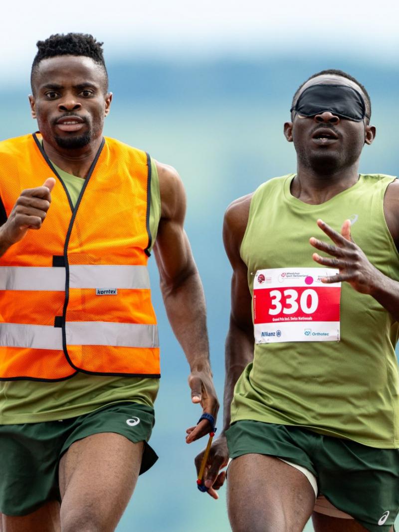 A male sprinter and his sighted guide competing