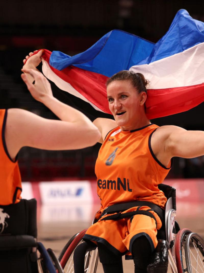 A female wheelchair basketball waves the Dutch flag to celebrate after a victory
