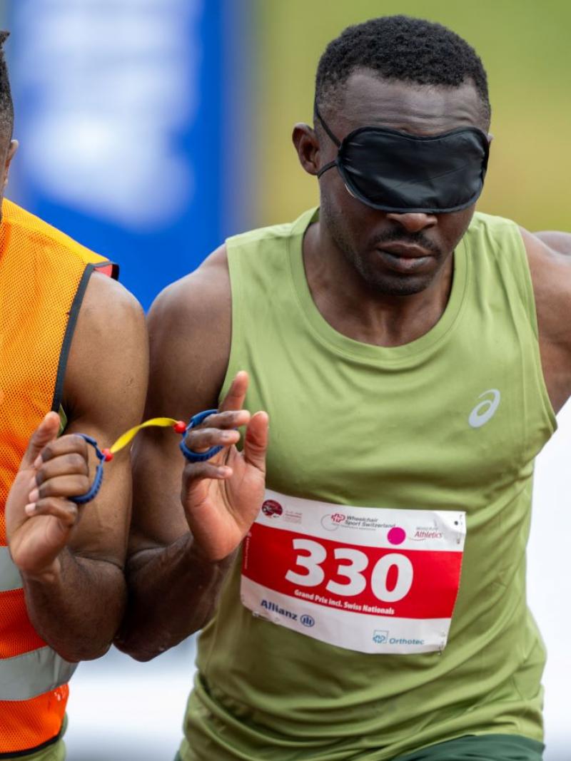 A male sprinter and his sighted guide runner competing.