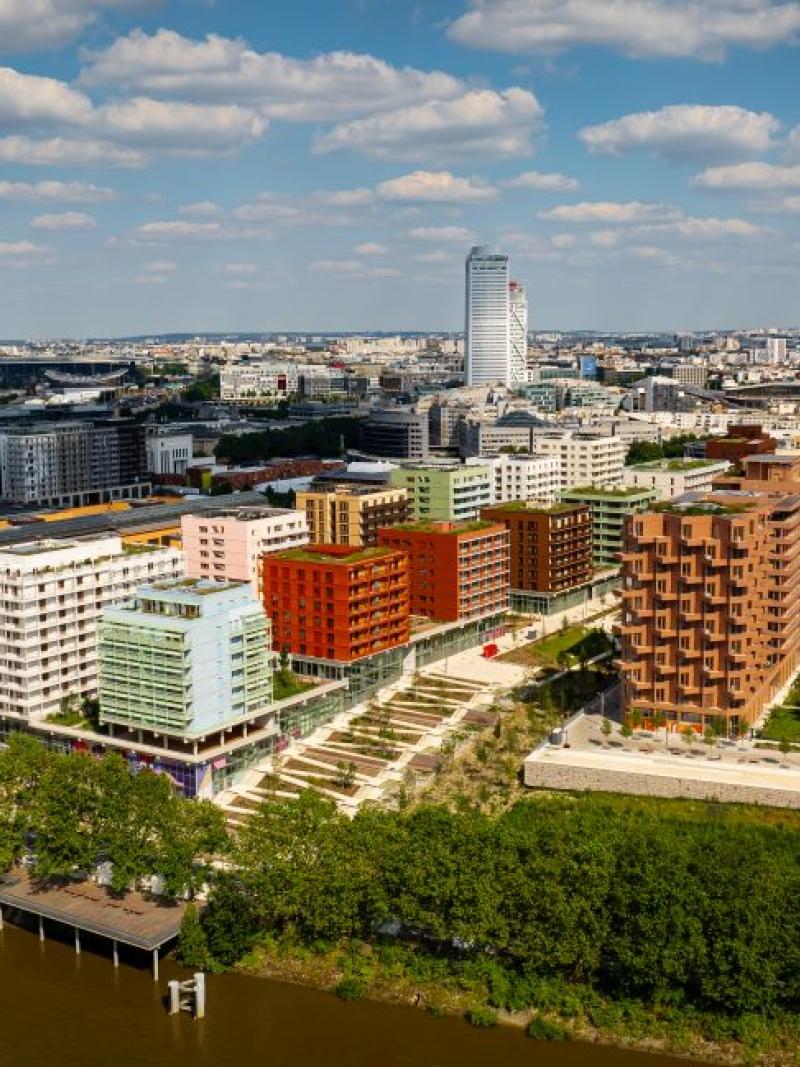 Photo taken from a drone shows the Paris 2024 Olympic and Paralympic Village. There are several buildings in front of a river.