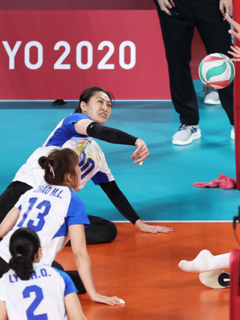 Yixiao Xu tries to get the ball over the net, while her opponent blocks.