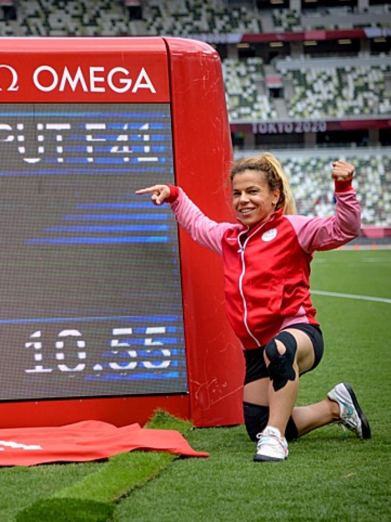 A woman pointing at a screen showing her world record mark in a stadium