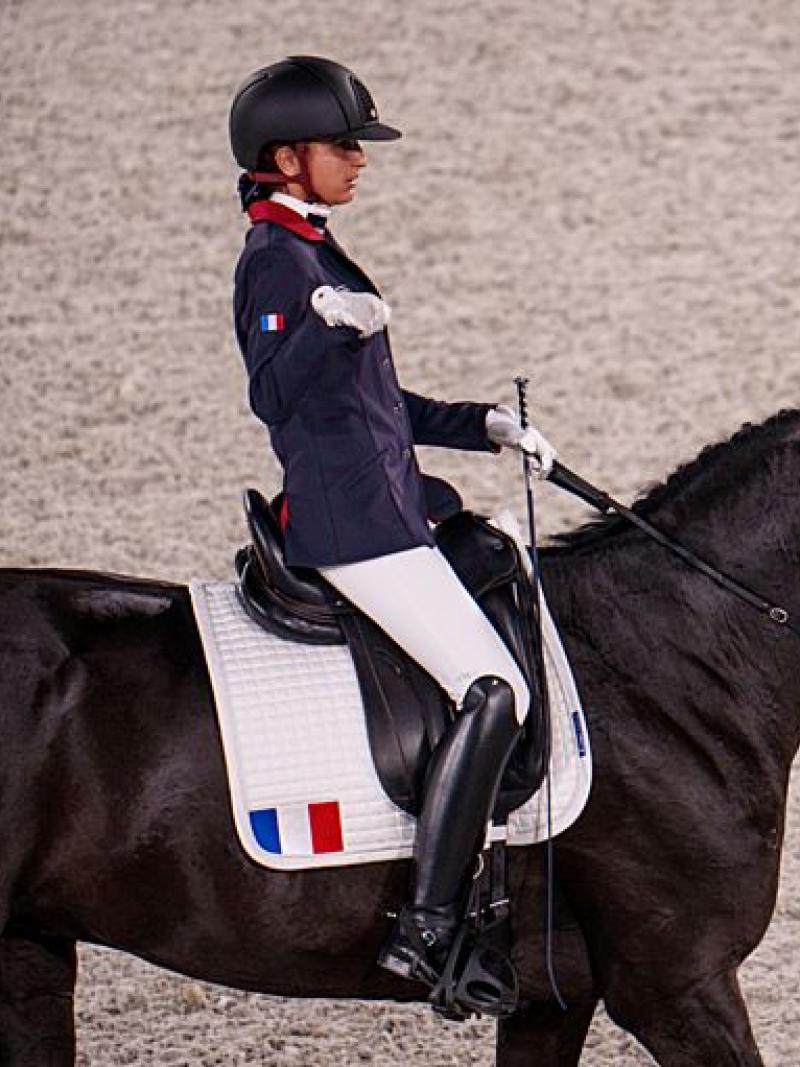A female Para equestrian athlete rides a horse