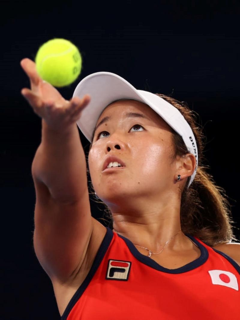 A female wheelchair tennis athlete throws the ball before a serve