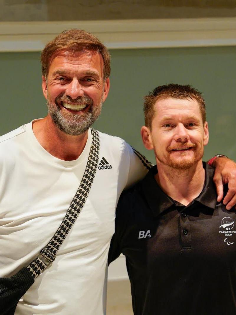 Man in a white tee with his arm round man in a black tee