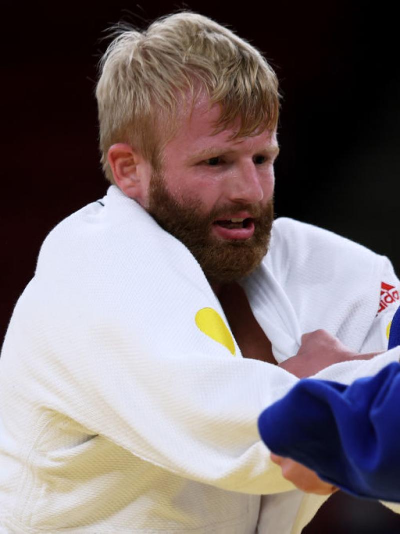 Two male judo athletes are grappling, grabbing their judogis during competition
