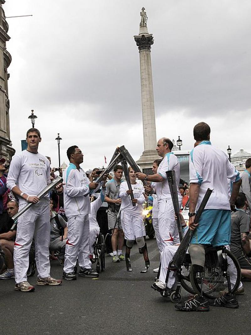 a group of Para athletes lighting a torch in front of Nelsons Column 