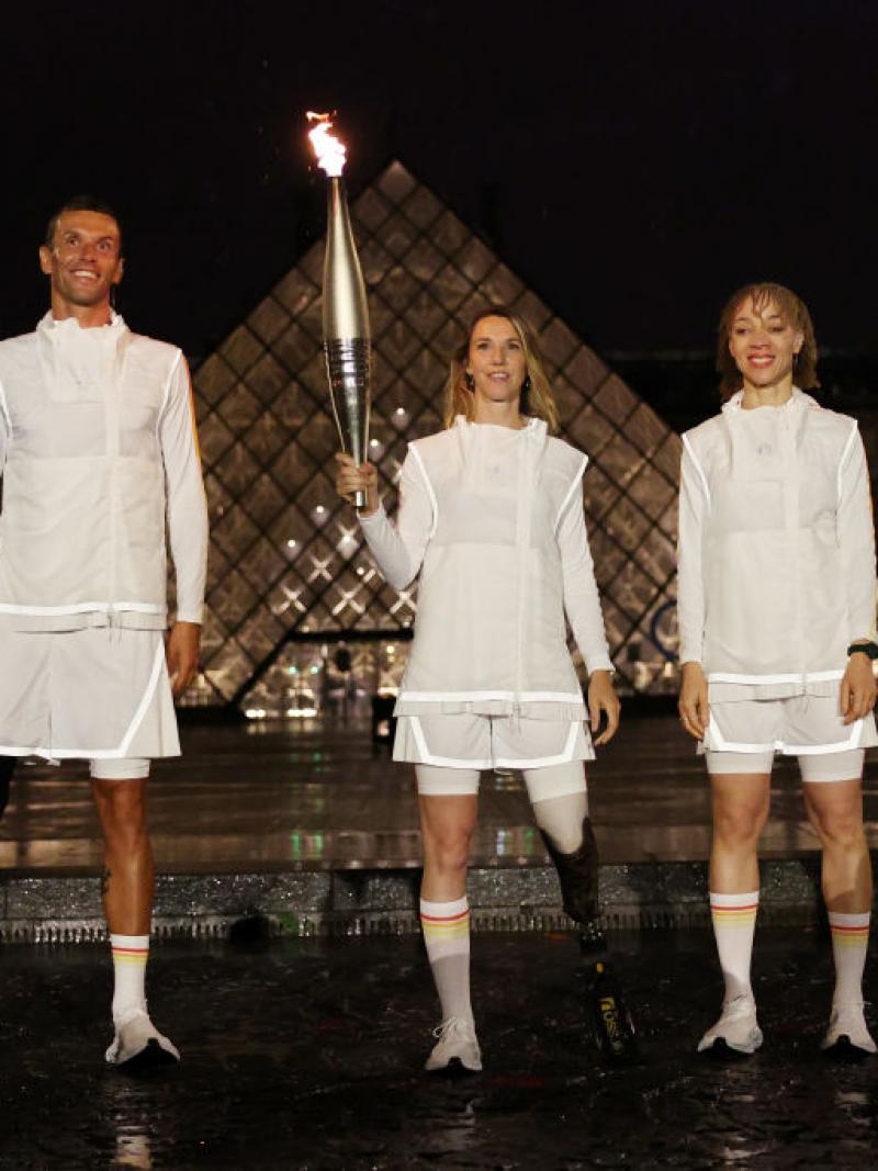 Marie-Amelie Le Fur holds the Olympic Torch in front of the Louvre