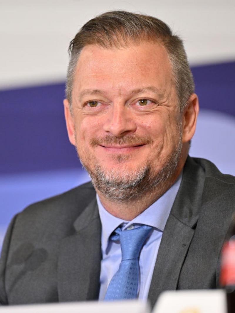 IPC President Andrew Parsons smiling in front of a microphone