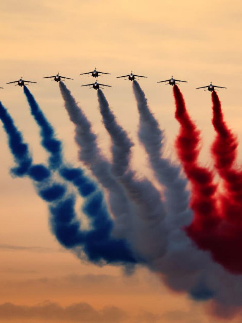 A group of planes flying in formation displaying coloured smoke