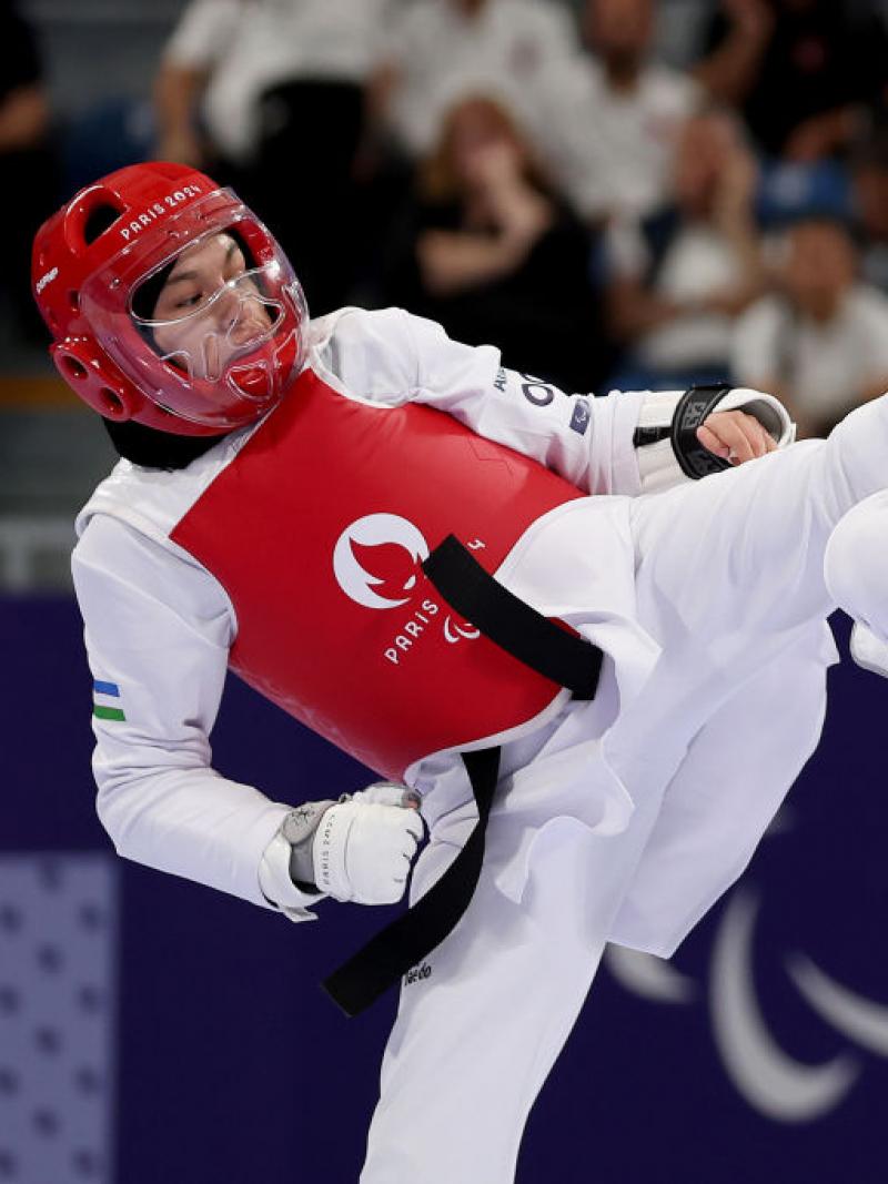 Two Para taekwondo competitors face each other at Paris 2024, one wearing red the other blue