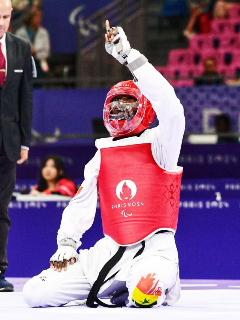 Para taekwondo fighter Idrissa Keita kneeling and pointing to the sky in celebration