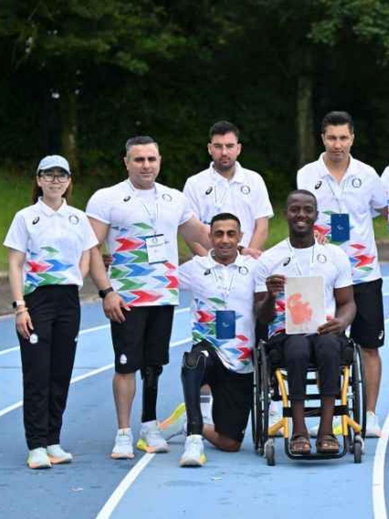 the Refugee Paralympic Team sitting and standing on an athletics track 