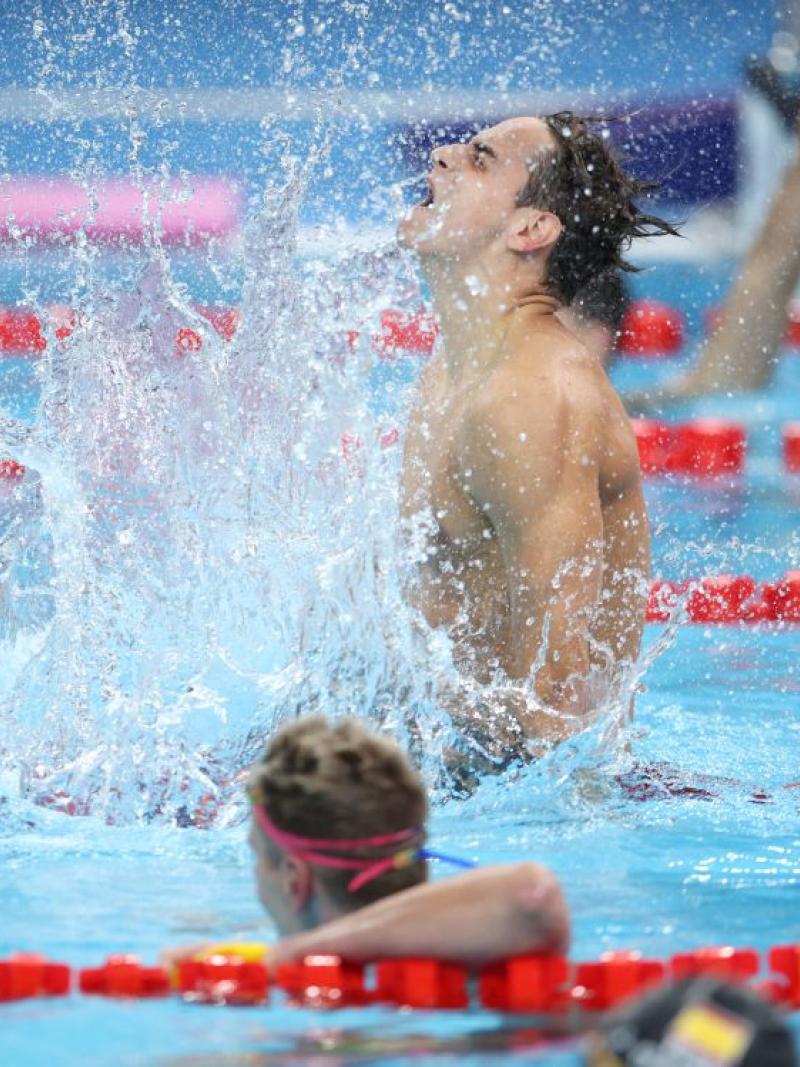 A swimmer celebrating in the water observed by three other swimmers