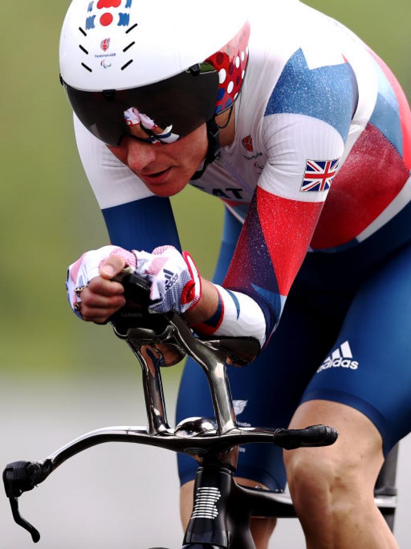A woman in a Great Britain uniform and helmet rides a racing bicycle at Tokyo 2020.