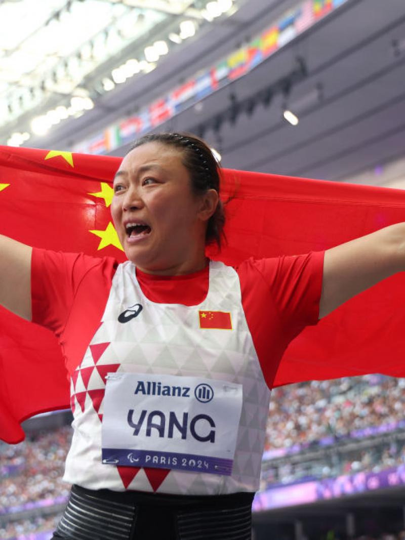 A female athlete with the Chinese flag in a packed stadium