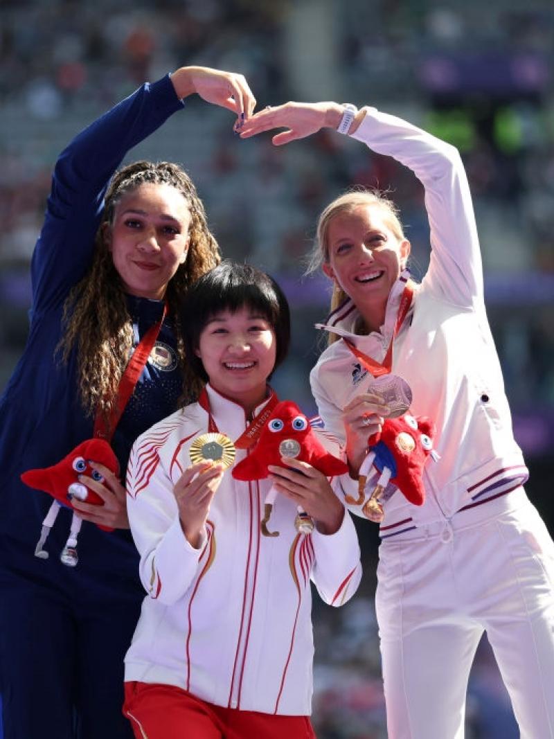 Three women on a podium celebrating their medals