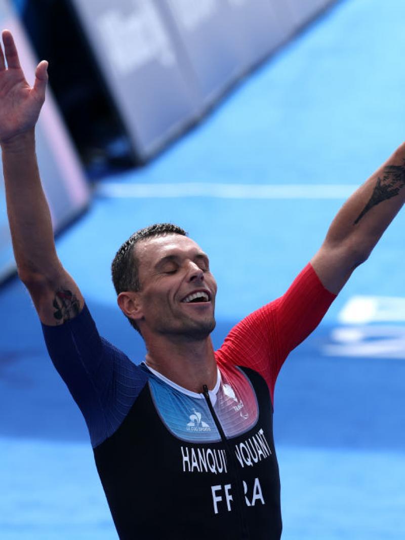 Para triathlete Alexis Hanquinquant raising his arms in celebration at the finish line