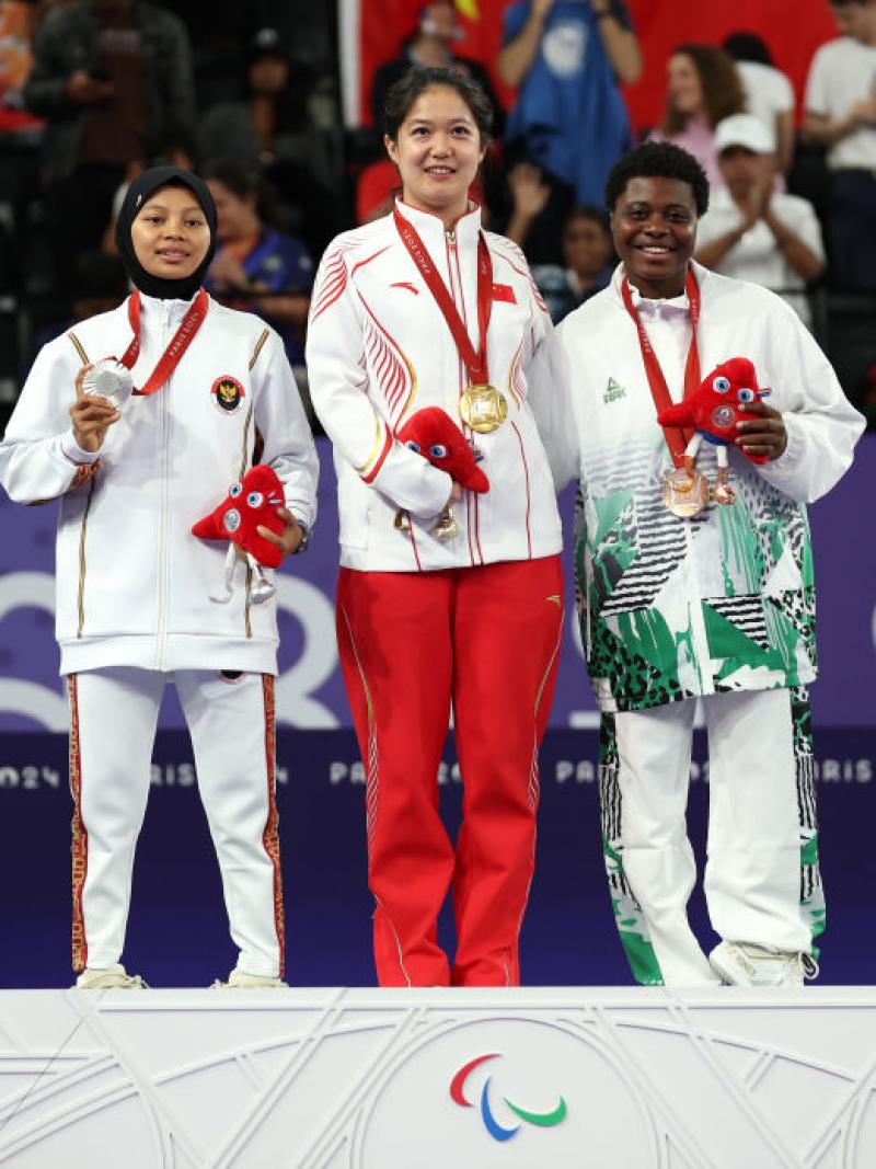 Three female Para badminton athletes with gold, silver and bronze medals on the podium