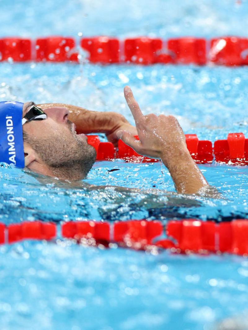 A male swimmer point his finger upwards in the pool