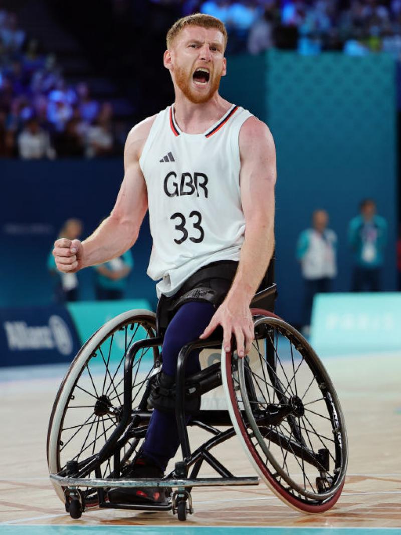 A man in a Great Britain uniform and a basketball wheelchair yells in celebration