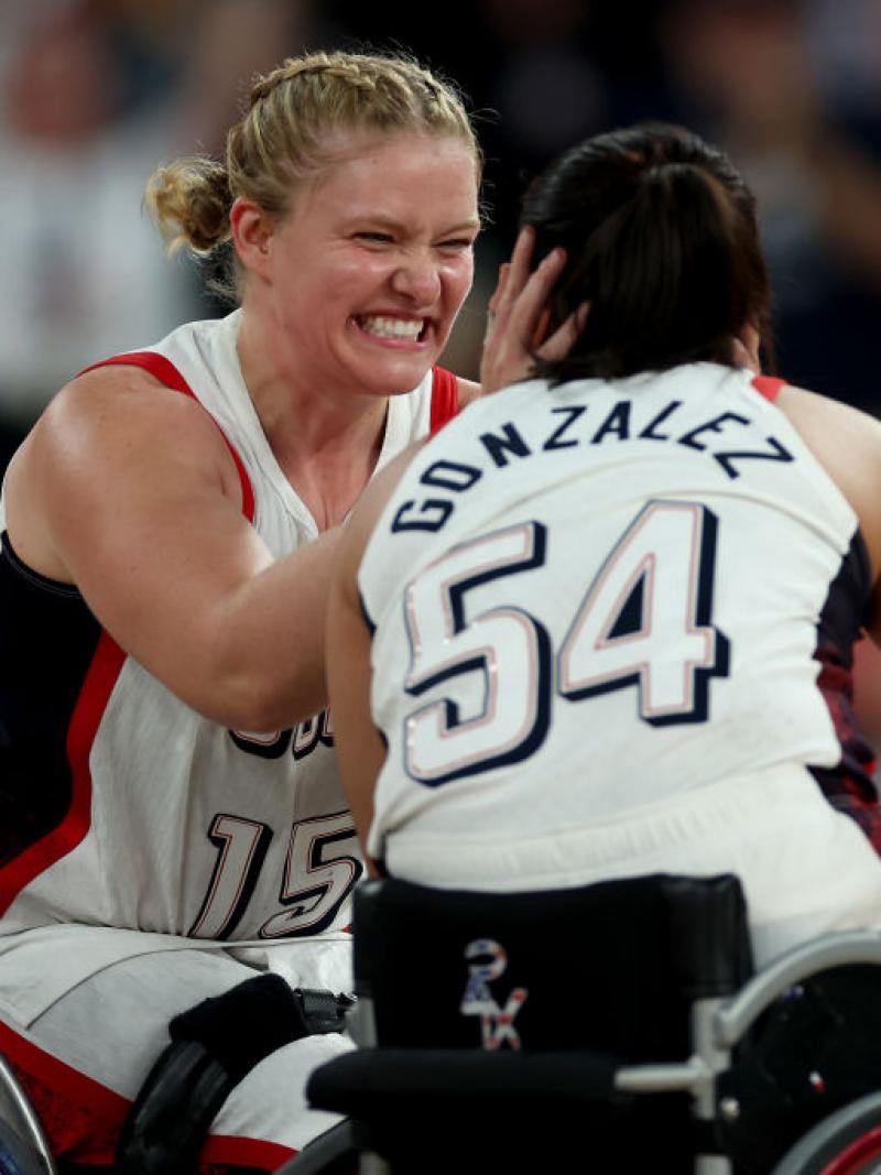Two female wheelchair basketballers hug in celebration on the court
