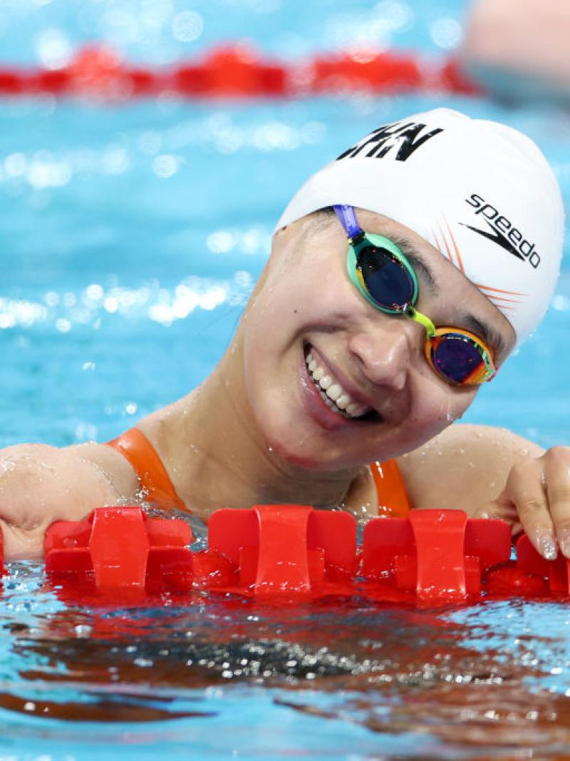 A female swimmer smiling from the pool