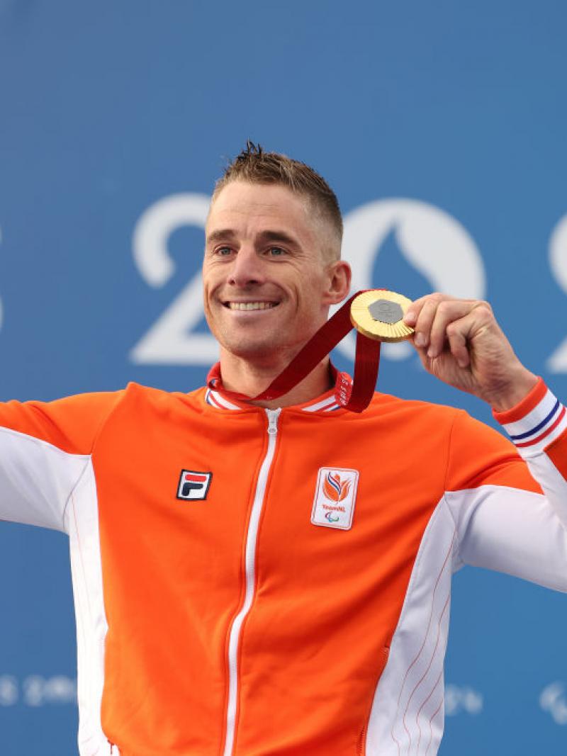 Para cyclist Jetze Plat holding up a gold medal and smiling 