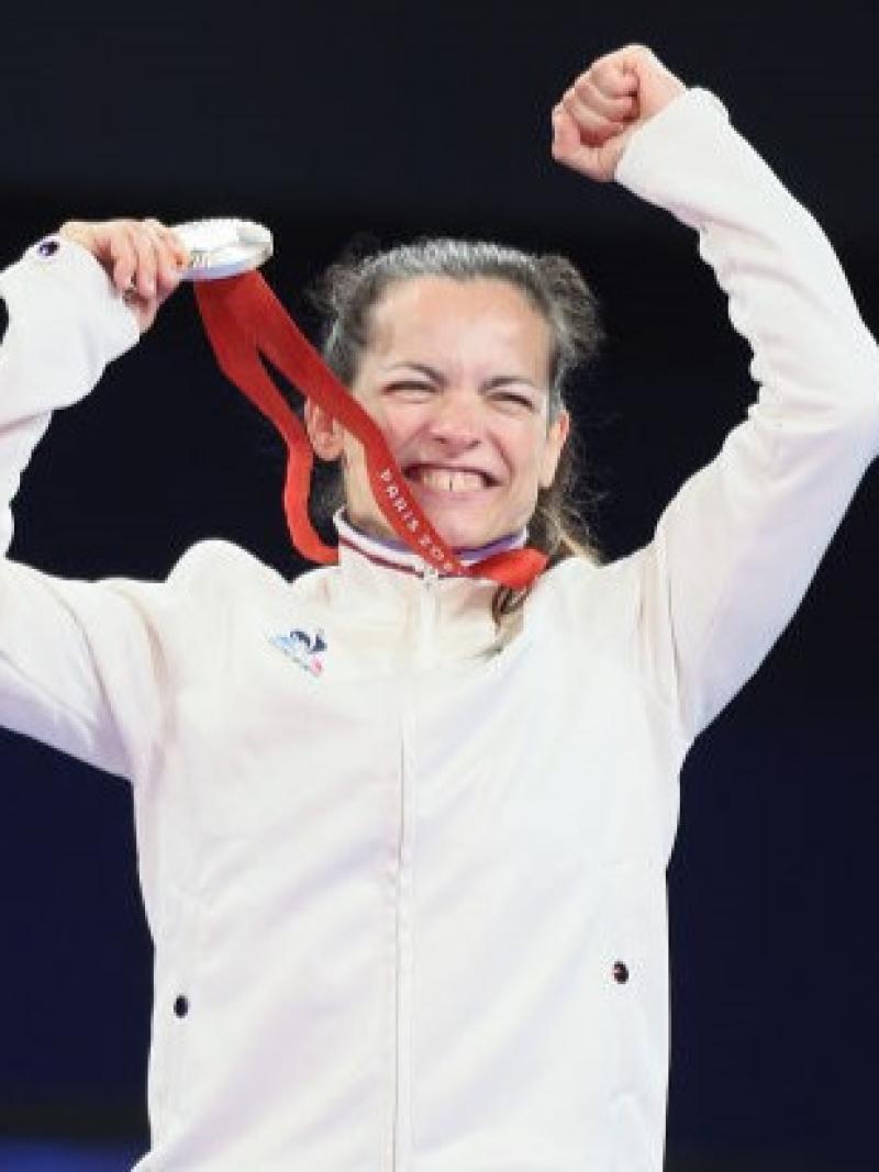 Para judoka Sandrine Martinet holding up a silver medal and smiling