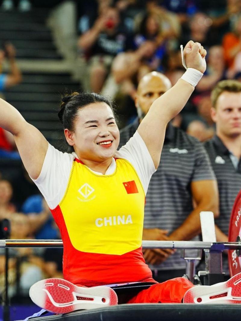 An athlete lifts her hands to celebrate after a successful lift