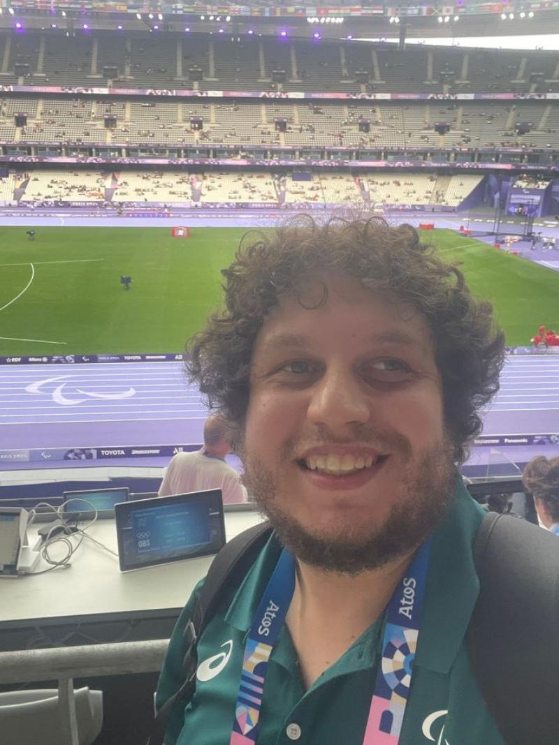 Harry De Cosemo, a male reporter, takes a selfie in front of the purple tracks at the Stade de France