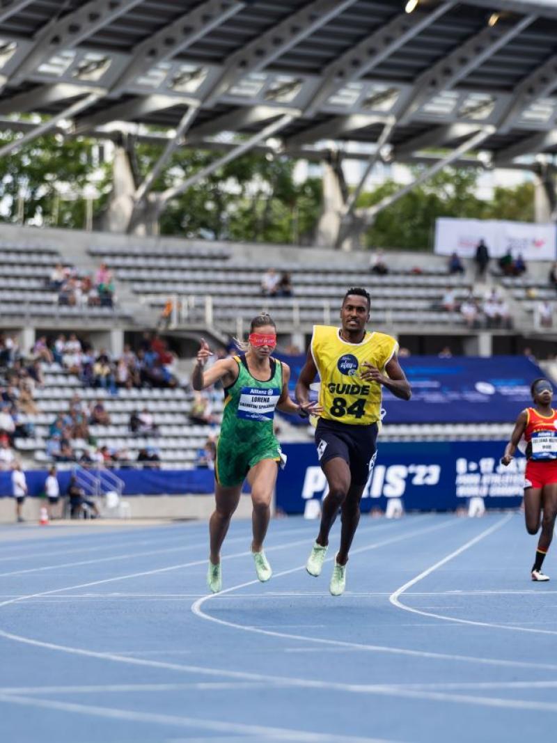 Three female runners with male guides in a Para athletics race