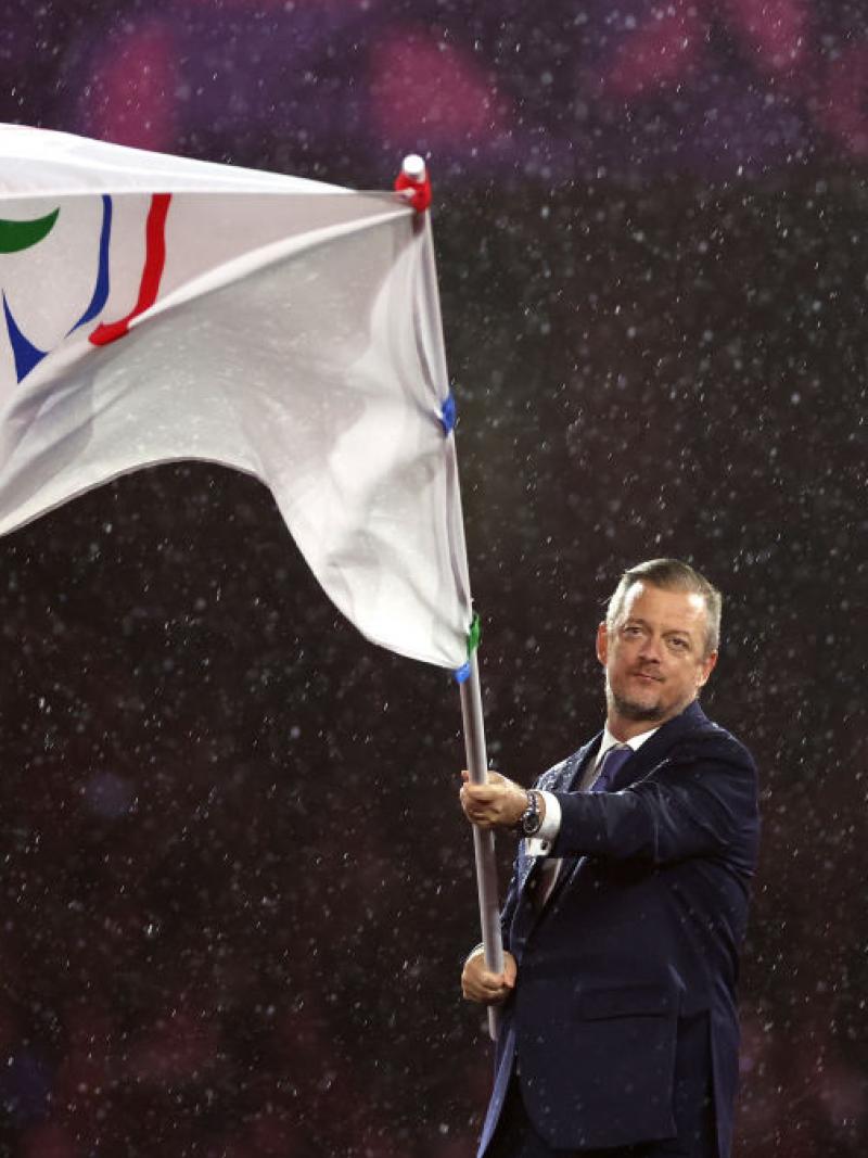 Andrew Parsons waves the flag of with the Paralympic symbol