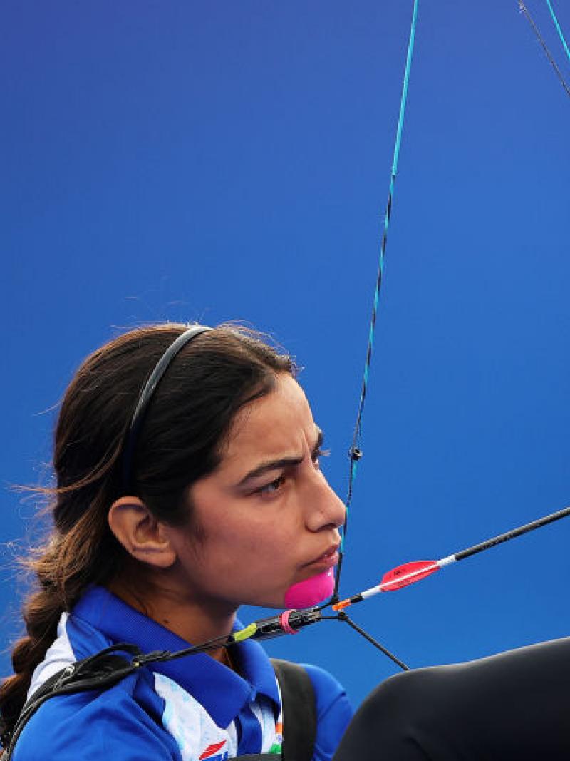 A female Para athlete prepares her bow with her right foot