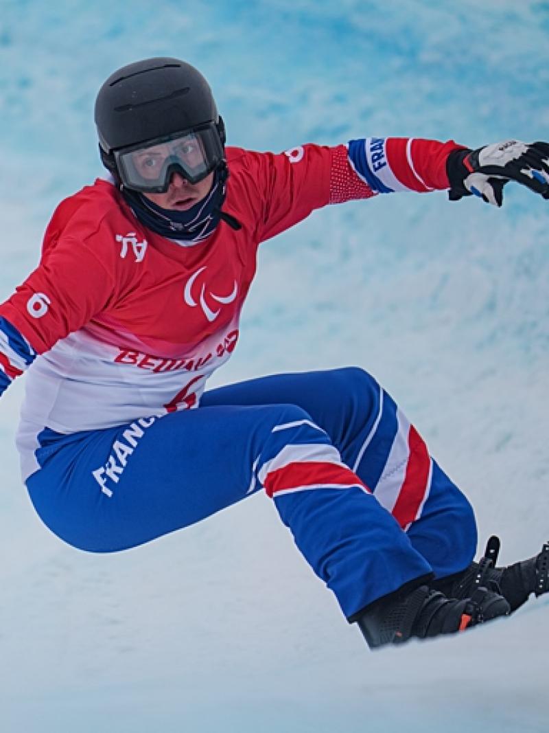 A male Para snowboard athlete competes at the Beijing 2022 Paralympic Winter Games