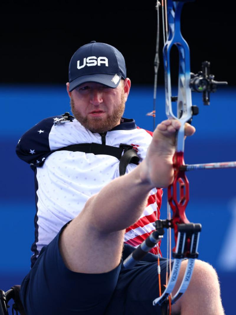 A male Para archer without arms shoots an arrow with his foot