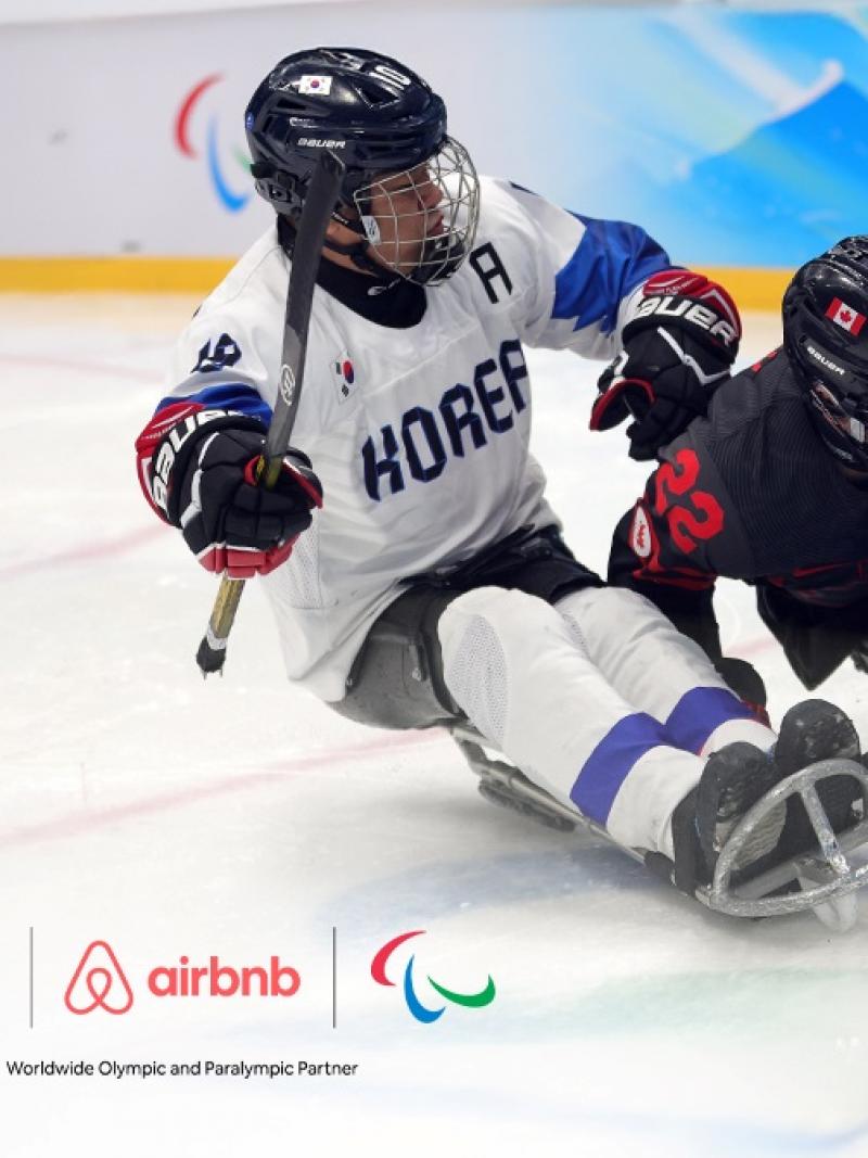 A banner with a photo of Para ice hockey players in action with the logo of Airbnb