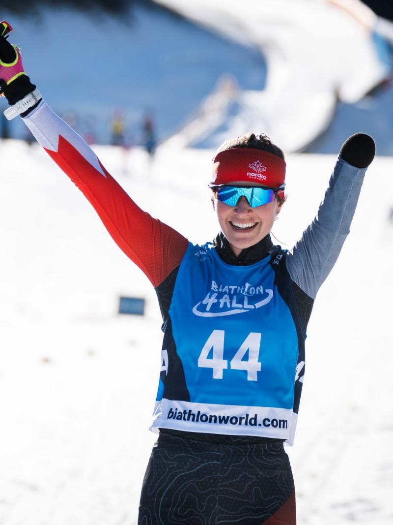 A female Para athlete wearing a ski gear raises her arms
