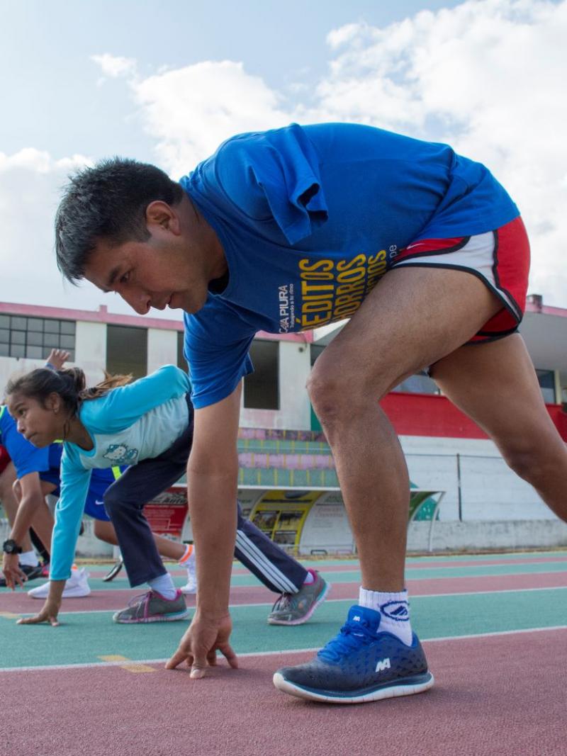 Five boys and girls with disabilities are bending down at the start line before racing at an outdoor track