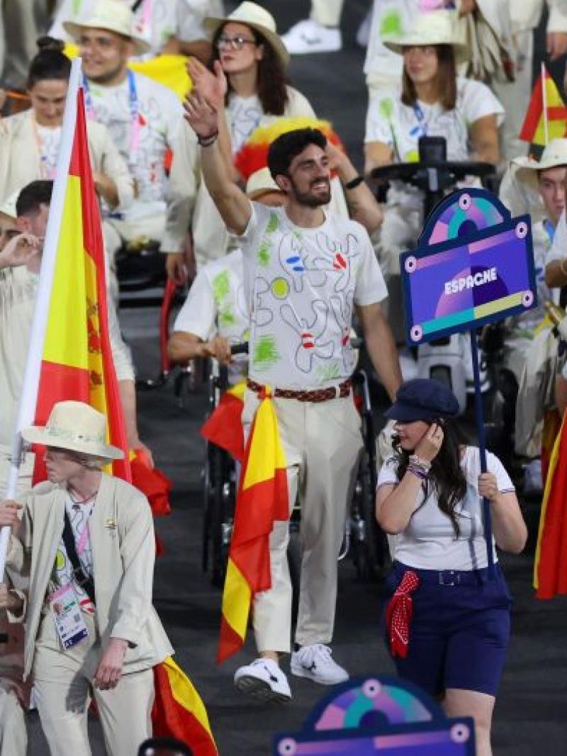 A large group of athletes taking part in the Parade of Nations at the Paris 2024 Opening Ceremony. They are holding the Spanish flag
