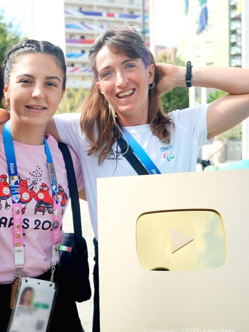 One male and three female athletes are posing with the golden plaque that is awarded to YouTube accounts with more than 1 million subscribers