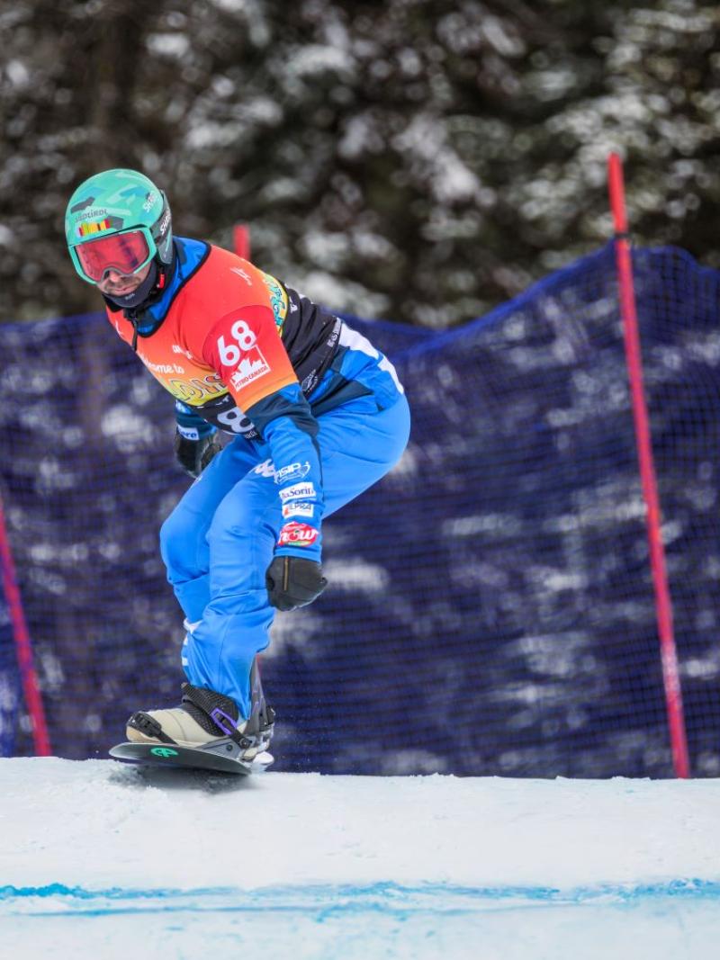 A male Para snowboard athlete is in competition.