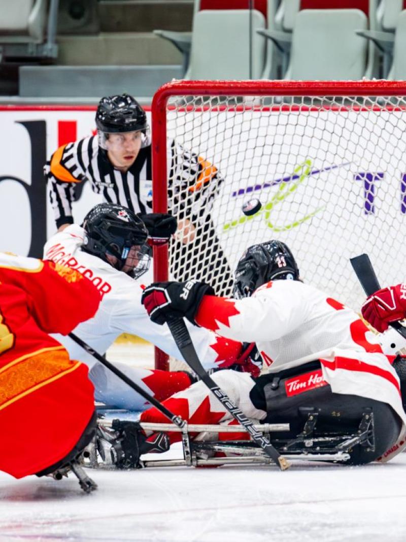 A Para ice hockey official watching four players