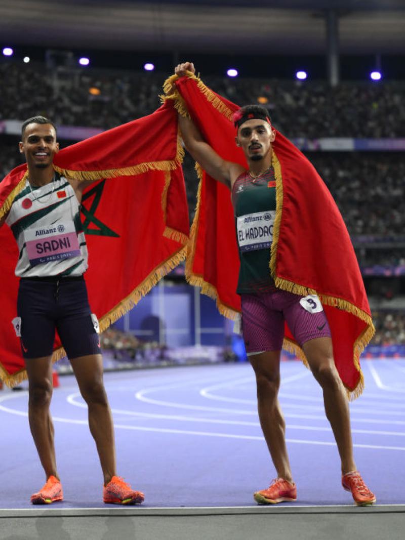 Two men with the Moroccan flag celebrating on the Stade de France athletics track