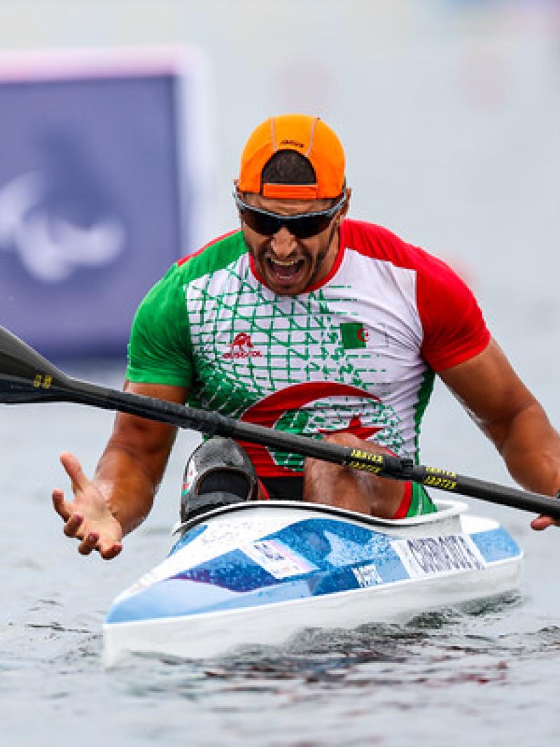 A male Para canoe athlete reacting with a roar after a race