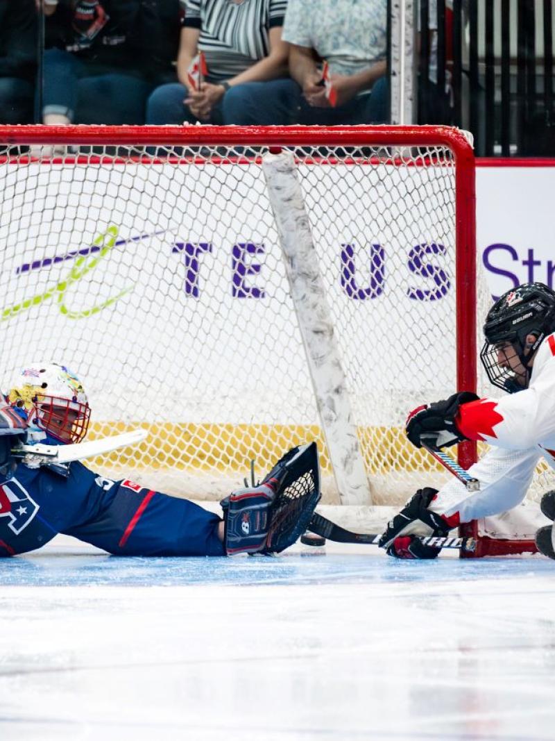 A Canadian Para ice hockey player scoring a goal against USA goaltender
