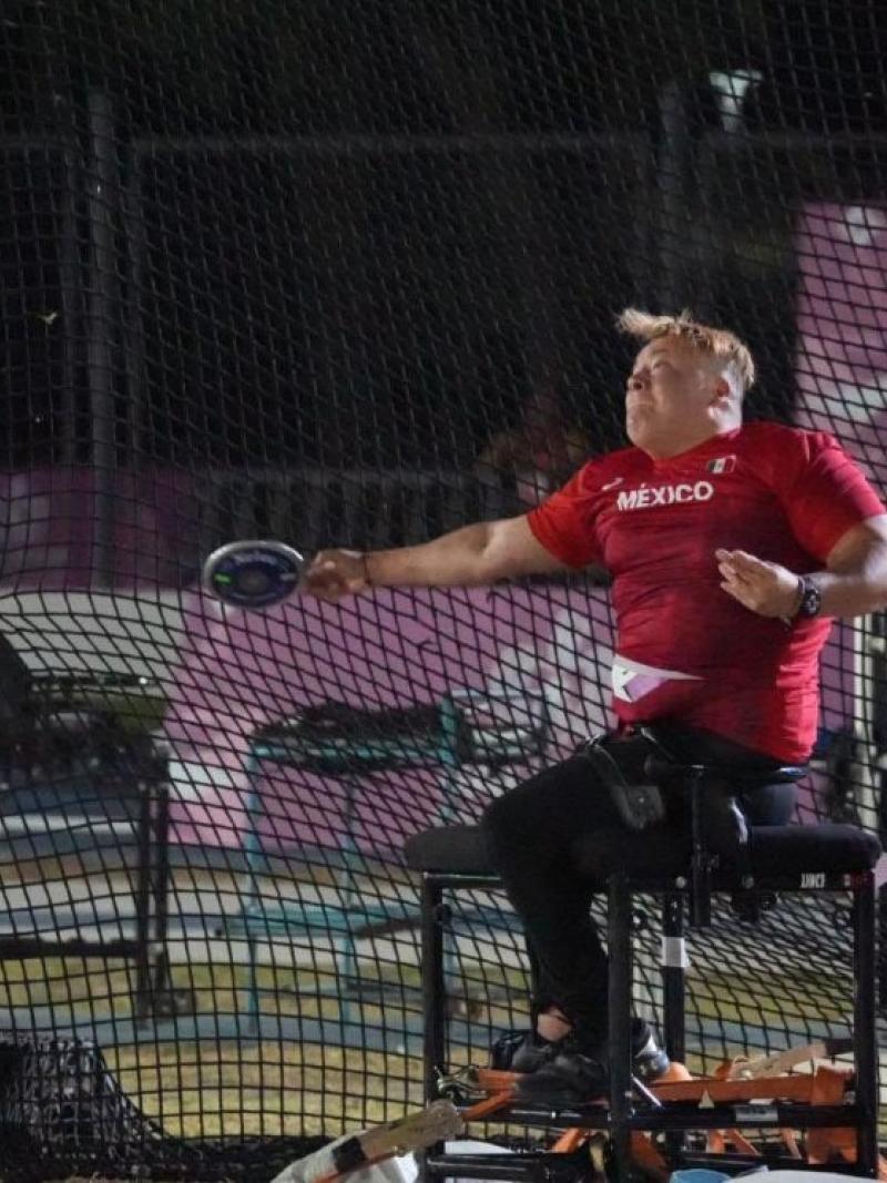 A female seated thrower competing observed by an official
