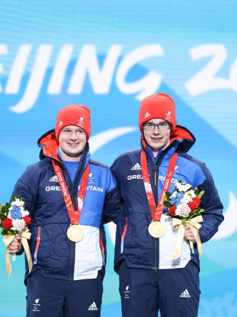 Two male athletes pose for a photograph on the podium after receiving gold medals